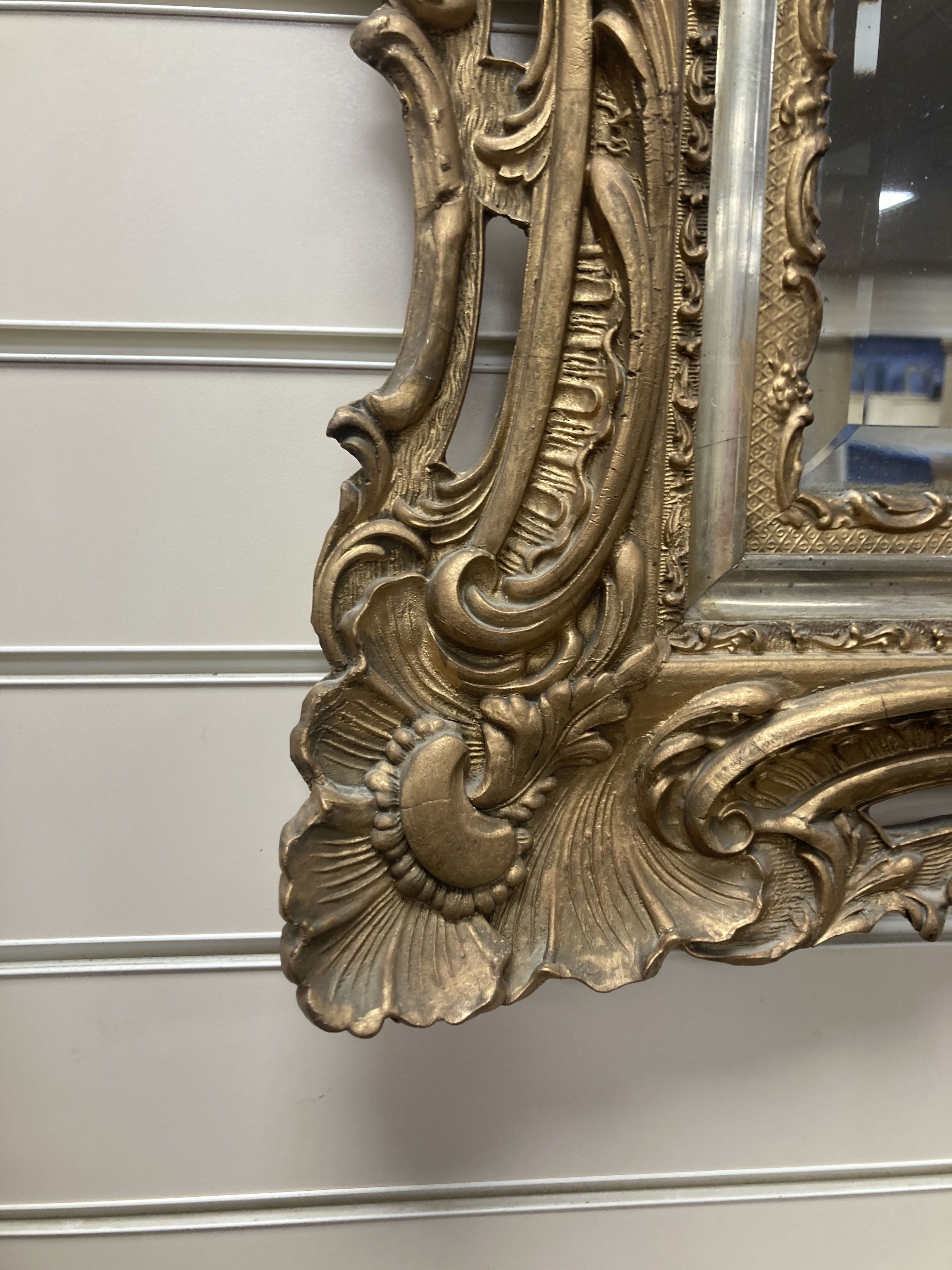 A rectangular carved and pierced framed gilt wall mirror in the rococo style, stepped and moulded border enclosing a bevelled plate, wi